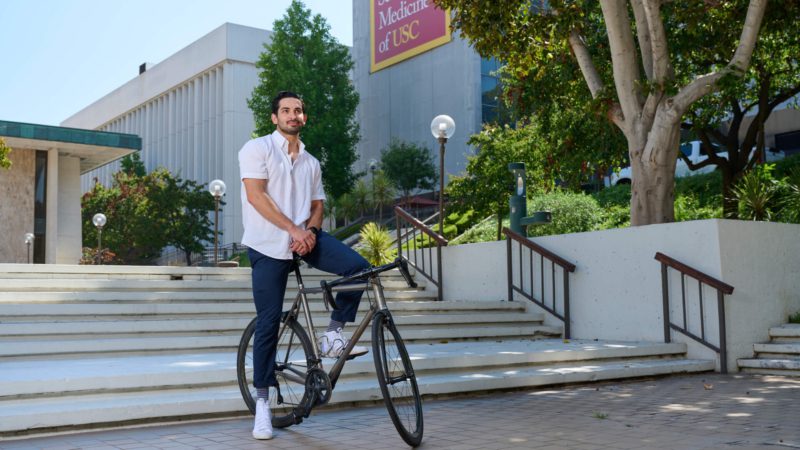 Sebouh J. Bazikian ’24, a student at the Keck School of Medicine of USC sitting on his bicycle at Pappas Quad, Health Science Campus