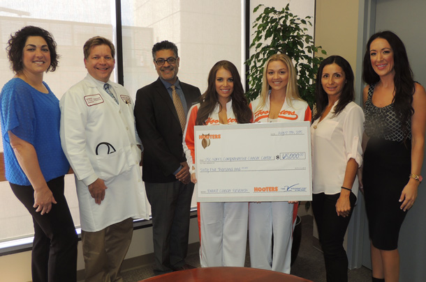 Jaime Valvano, at left, of the V Foundation for Cancer Research and three representatives from Hooters of Orange County present a check to USC Norris Director Stephen B. Gruber, second from left. Also pictured, from Gruber's left, are Zul Surani, executive director of the HSC Community Partnerships Office in Civic Engagement, Jordyne Chessmore and Shelby Tweeten of Hooters, Elena Nieves, Clinical Trials Outreach and Enrollment coordinator, and Melissa Fry, director of marketing for Hooters.