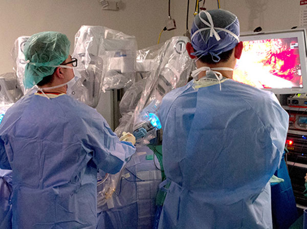 Members of the medical team watch a robot-assisted spinal tumor surgery with Patrick Hsieh, MD, and Andrew Hung, MD.