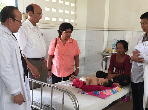 Shri Mishra, second from left, and Soma Sahai-Srivastava, center, look at a child in a clinic in Cambodia during a July 2015 trip to the country. Sahai is spearheading a group of medical professionals from the Keck School who are developing a neurology outreach program for Cambodian health care professionals funded by a grant from the World Federation of Neurology.