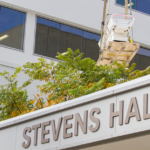 A picture of Stevens Hall with the 7T MRI being lowered into it ceiling.