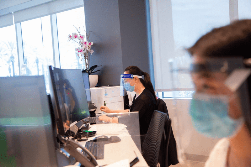 Two Asian American healthcare workers with face masks at a desk.