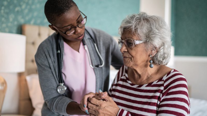 Home caregiver helping a senior woman standing in the bedroom