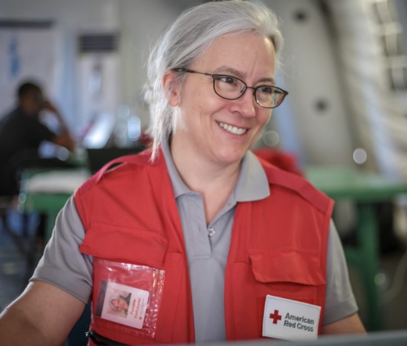 A woman smiling in a Red Cross uniform vest