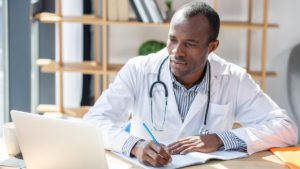 Doctor sitting attentively in front of laptop.