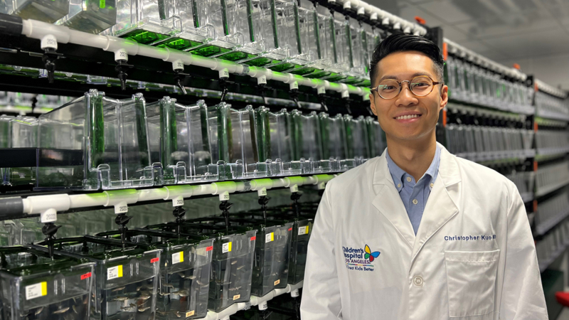 Dr. Kuo stands before banks of Zebrafish tanks, which he uses to seek improved treatments for Ewing sarcoma. (Photo by Dr. Julia Ma)