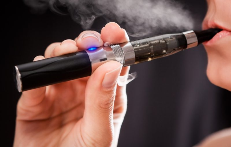 Close up of a woman inhaling from an electronic cigarette